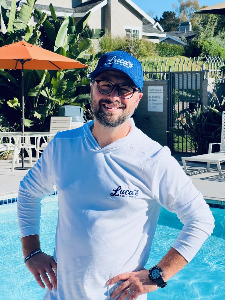 Luca, owner of Luca’s Pool Services, standing beside a swimming pool